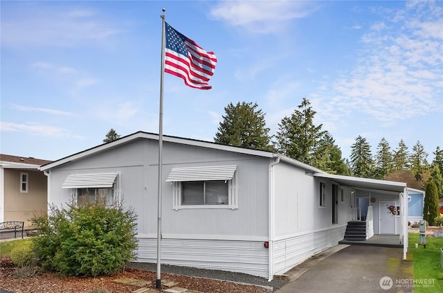 manufactured / mobile home with entry steps, an attached carport, and driveway