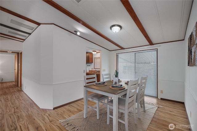 dining room with light wood-style flooring, vaulted ceiling with beams, and baseboards