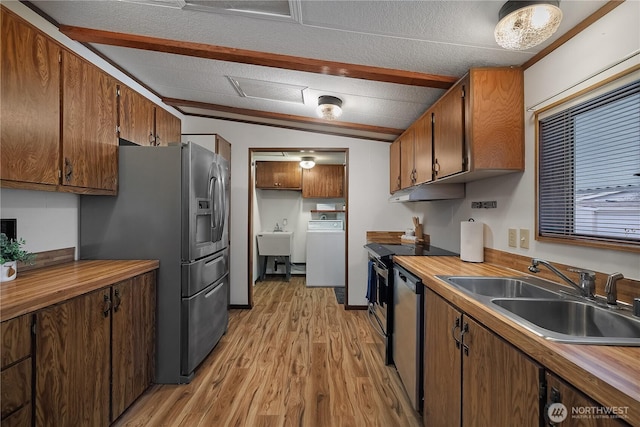 kitchen with light wood-style flooring, washer / clothes dryer, stainless steel appliances, a sink, and vaulted ceiling