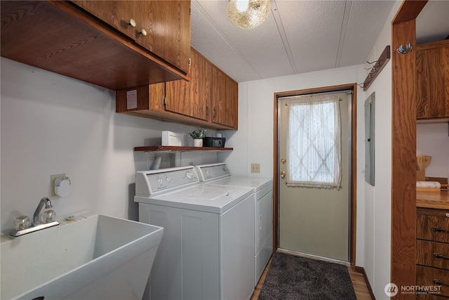 laundry area featuring independent washer and dryer, a sink, electric panel, a textured ceiling, and cabinet space