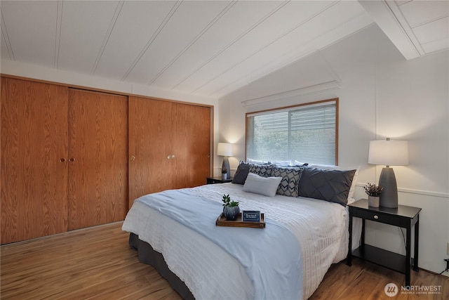 bedroom with a closet, vaulted ceiling, and wood finished floors