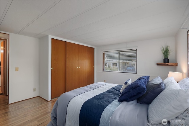 bedroom with baseboards, a closet, and light wood finished floors