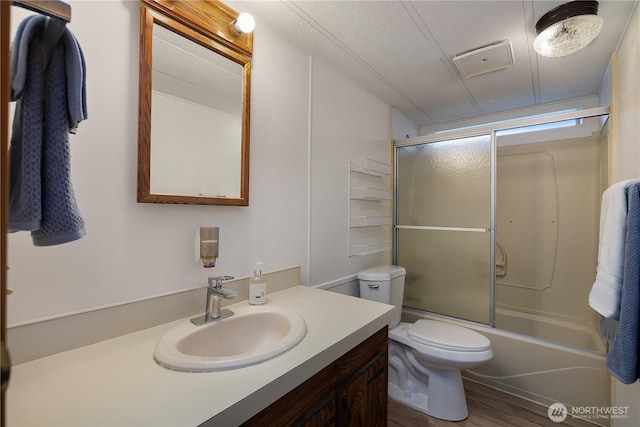 bathroom featuring combined bath / shower with glass door, toilet, wood finished floors, and vanity