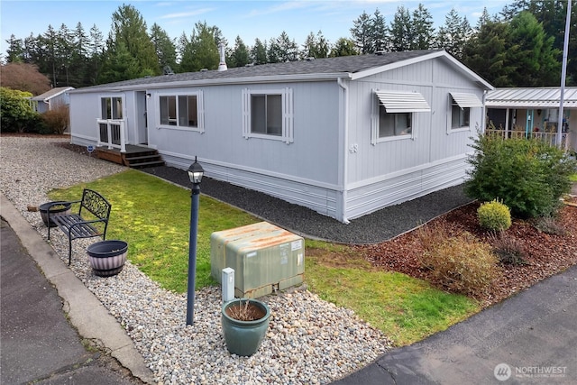 manufactured / mobile home featuring a shingled roof and a front lawn