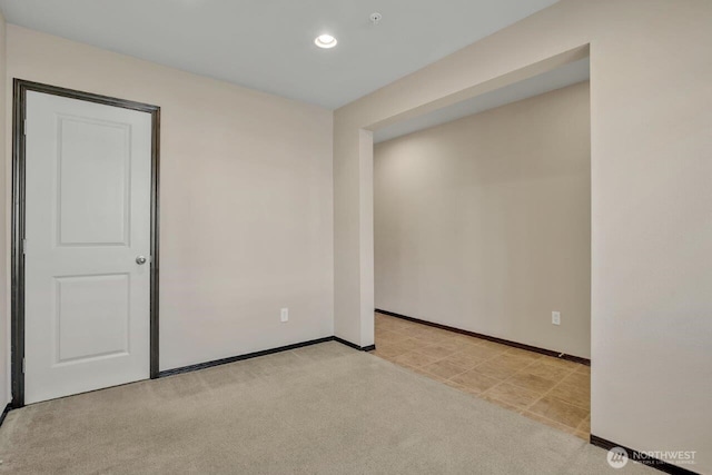 spare room featuring light carpet, recessed lighting, and baseboards