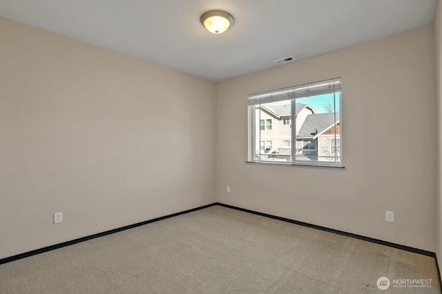 spare room with carpet floors, visible vents, and baseboards