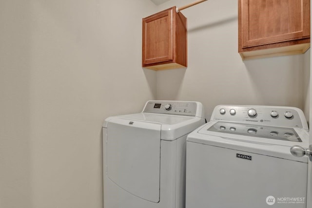 clothes washing area featuring cabinet space and washing machine and clothes dryer