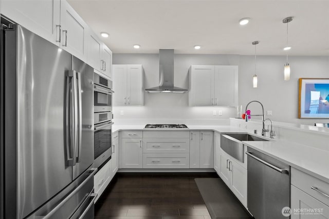 kitchen featuring stainless steel appliances, dark wood-style flooring, a sink, light countertops, and wall chimney exhaust hood