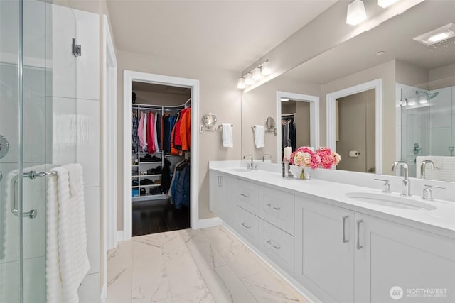 bathroom featuring marble finish floor, a sink, a shower stall, and double vanity