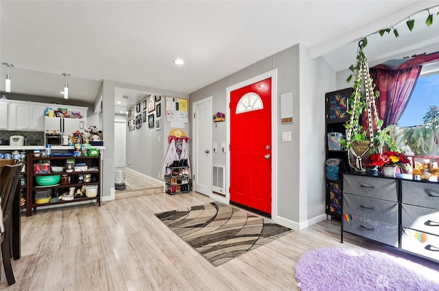 entryway with light wood-style floors, baseboards, and visible vents