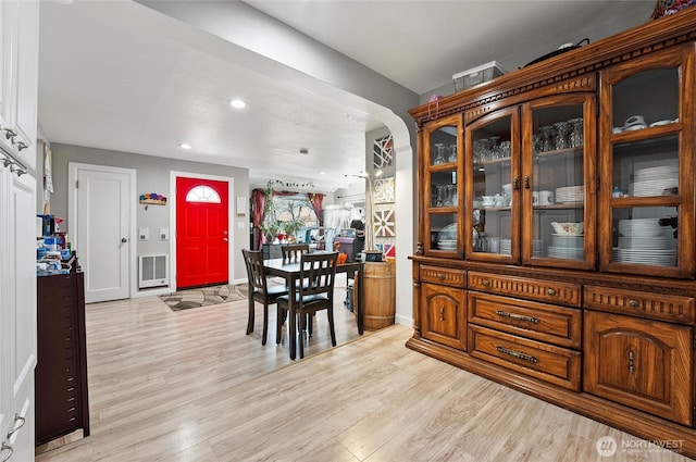 dining area featuring baseboards, arched walkways, heating unit, light wood-type flooring, and recessed lighting