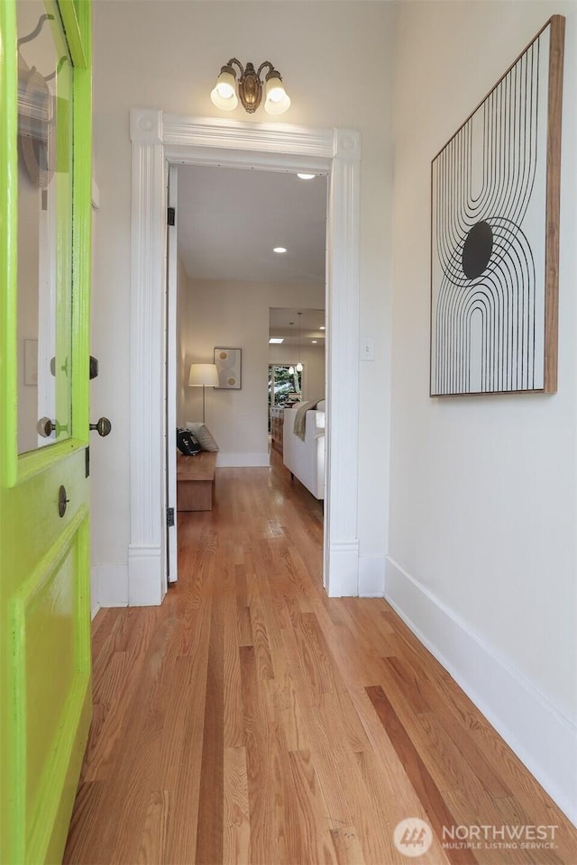 corridor featuring light wood finished floors and baseboards