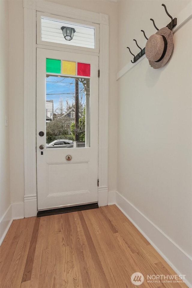 doorway with a wealth of natural light, light wood-type flooring, and baseboards