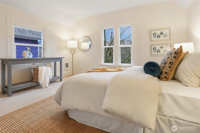 bedroom featuring lofted ceiling, visible vents, baseboards, and carpet flooring