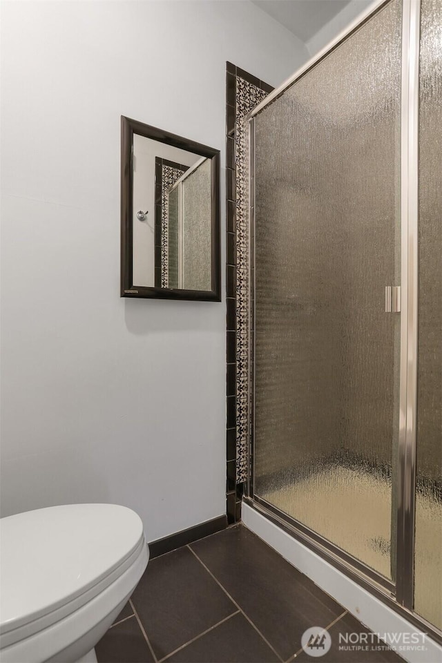 full bathroom with toilet, a shower stall, baseboards, and tile patterned flooring