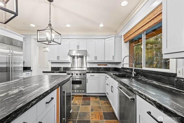 kitchen with premium appliances, under cabinet range hood, a sink, stone finish floor, and crown molding