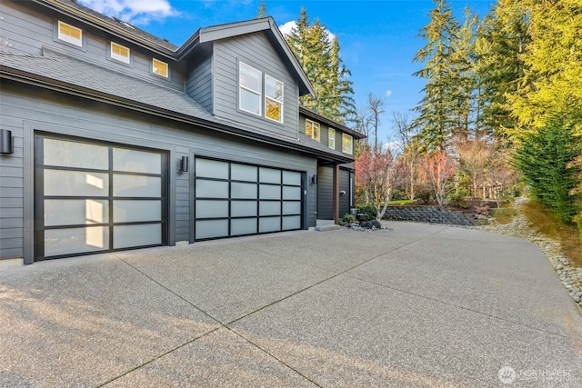 view of home's exterior featuring a garage, a shingled roof, and concrete driveway