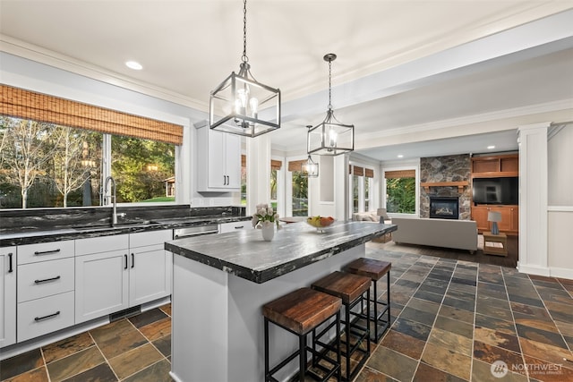 kitchen featuring stone tile floors, a breakfast bar, a fireplace, a kitchen island, and a sink