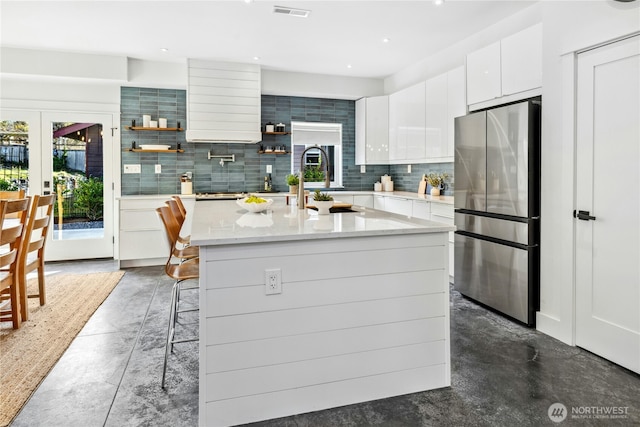 kitchen featuring visible vents, freestanding refrigerator, white cabinetry, open shelves, and backsplash