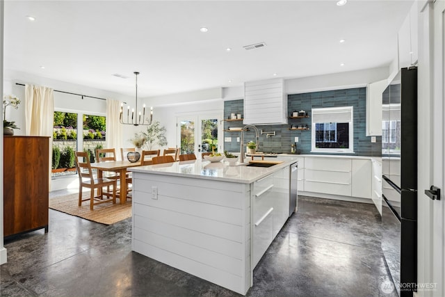 kitchen with a healthy amount of sunlight, refrigerator with glass door, modern cabinets, and finished concrete floors