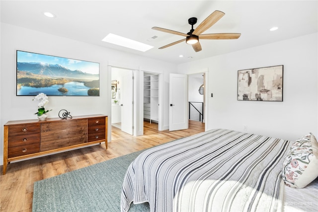 bedroom with a skylight, a spacious closet, wood finished floors, and recessed lighting