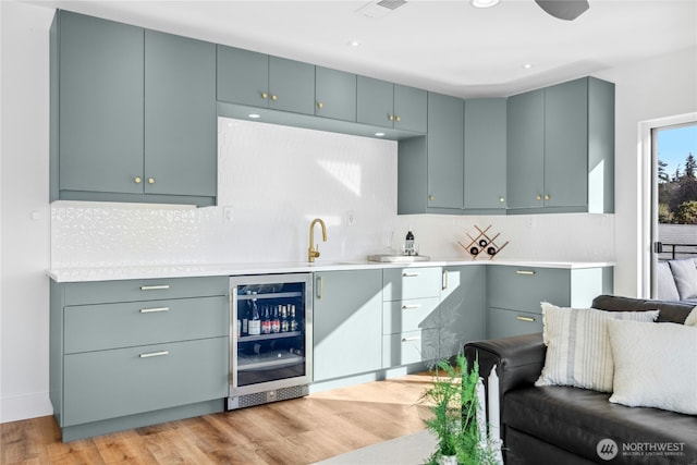 kitchen with wine cooler, visible vents, light wood-style floors, light countertops, and decorative backsplash