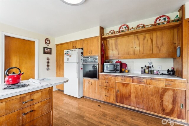 4421 89th Ave SE, Olympia, WA 98501 - kitchen with stainless steel microwave, black oven, light countertops, freestanding refrigerator, and brown cabinetry