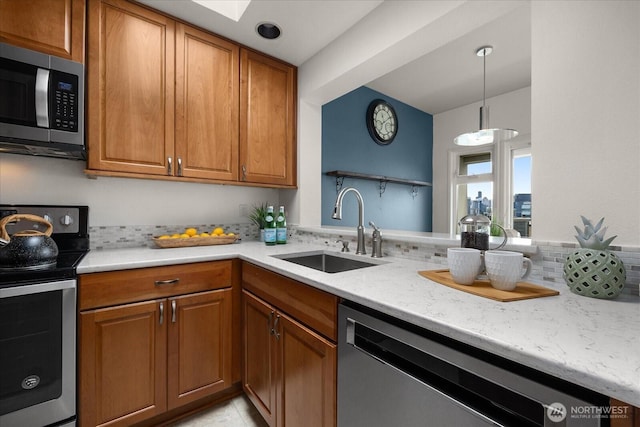 kitchen with stainless steel appliances, brown cabinets, a sink, and hanging light fixtures