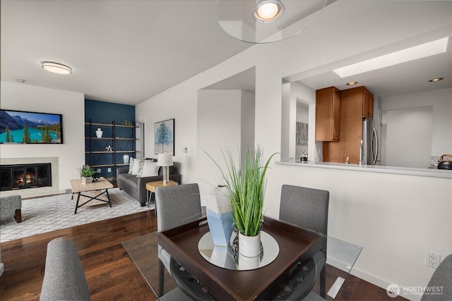 dining area with dark wood finished floors and a glass covered fireplace