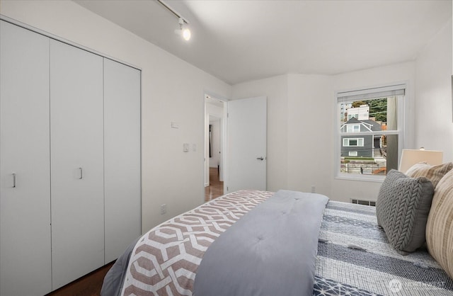 bedroom with rail lighting, visible vents, and a closet