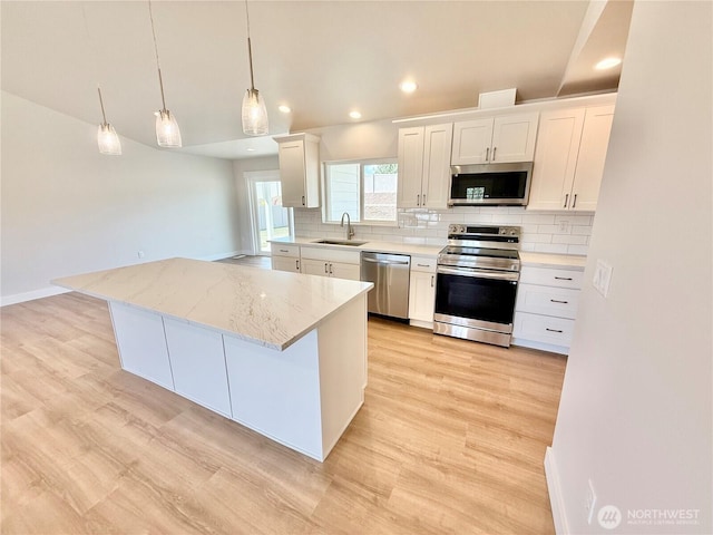 2575 1st St SE, East Wenatchee, WA 98802 - kitchen featuring stainless steel appliances, decorative backsplash, white cabinetry, a center island, and pendant lighting
