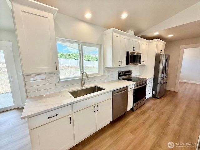 2575 1st St SE, East Wenatchee, WA 98802 - kitchen featuring appliances with stainless steel finishes, decorative backsplash, white cabinetry, vaulted ceiling, and light wood finished floors