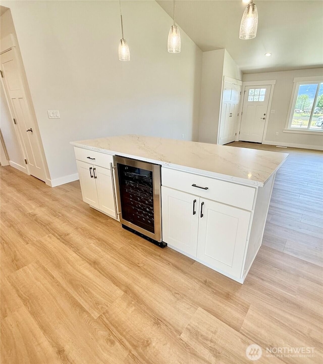 2575 1st St SE, East Wenatchee, WA 98802 - kitchen with beverage cooler, light wood-type flooring, pendant lighting, white cabinetry, and light stone counters