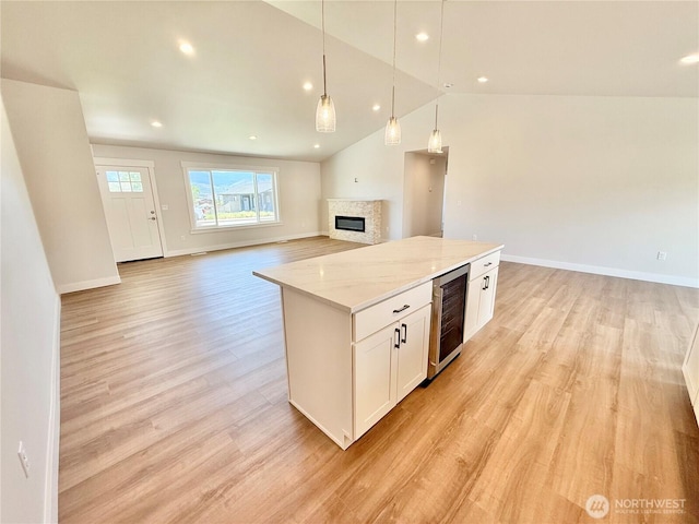 2575 1st St SE, East Wenatchee, WA 98802 - kitchen featuring beverage cooler, open floor plan, white cabinets, a glass covered fireplace, and a kitchen island