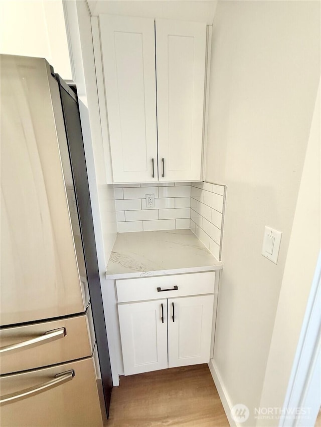 2575 1st St SE, East Wenatchee, WA 98802 - kitchen with freestanding refrigerator, light wood-style floors, light stone countertops, tasteful backsplash, and white cabinets