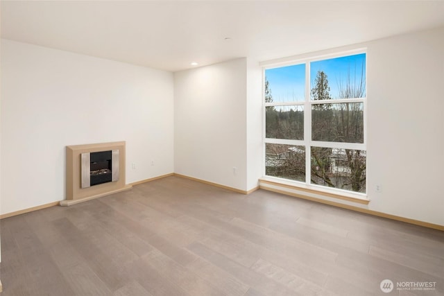 unfurnished living room with recessed lighting, wood finished floors, and baseboards