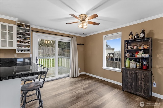 dining space featuring ornamental molding, a ceiling fan, baseboards, and wood finished floors