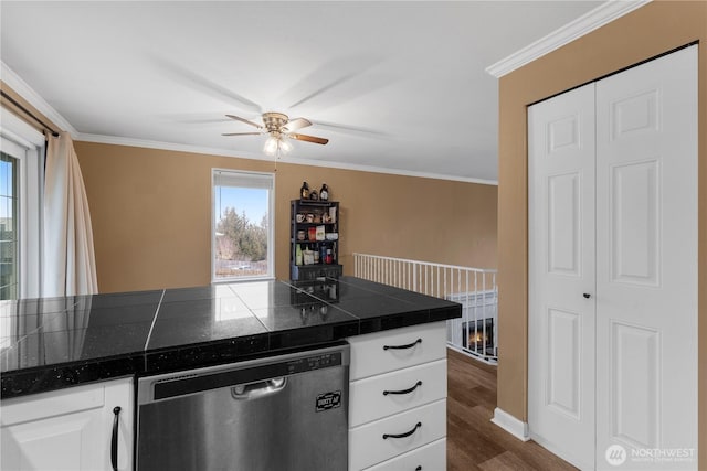 kitchen with dark wood-style floors, stainless steel dishwasher, ornamental molding, and white cabinets