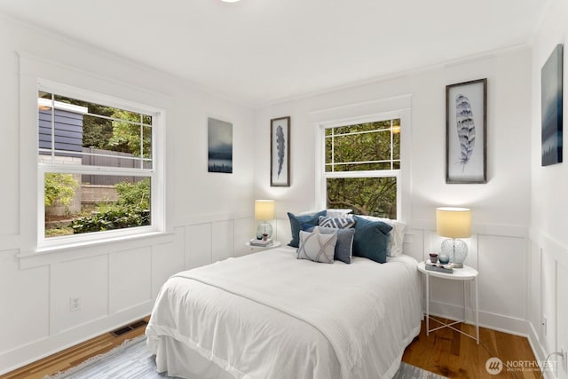 3657 23rd Ave W, Seattle, WA 98199 - bedroom with multiple windows, a decorative wall, a wainscoted wall, wood finished floors, and ornamental molding