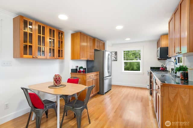 3657 23rd Ave W, Seattle, WA 98199 - kitchen featuring appliances with stainless steel finishes, light wood finished floors, glass insert cabinets, recessed lighting, and brown cabinetry