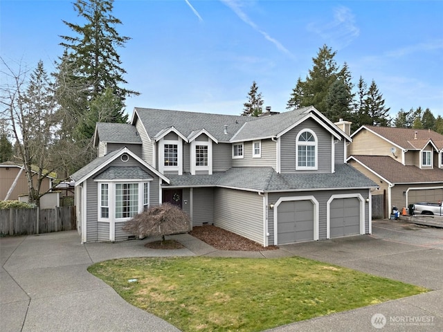 traditional home featuring driveway, roof with shingles, an attached garage, and fence