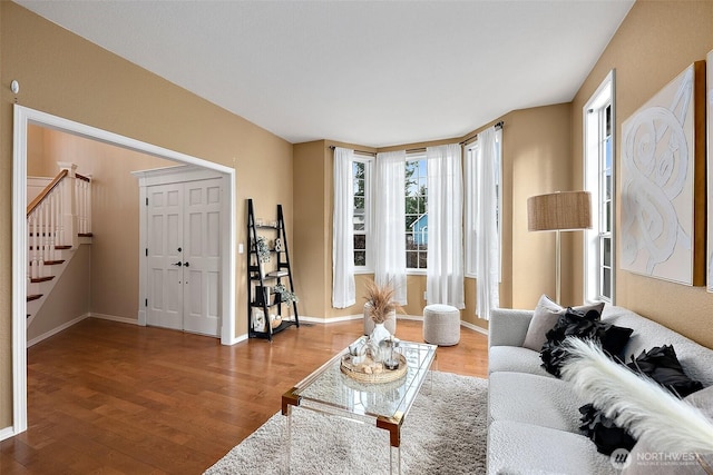 living room with stairs, baseboards, and wood finished floors