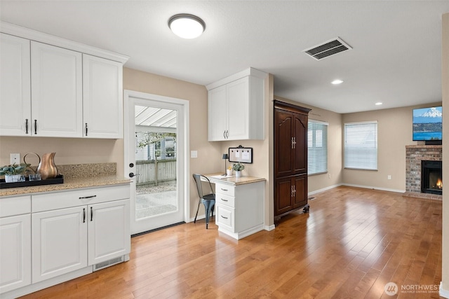 kitchen featuring visible vents, a fireplace, and light wood finished floors