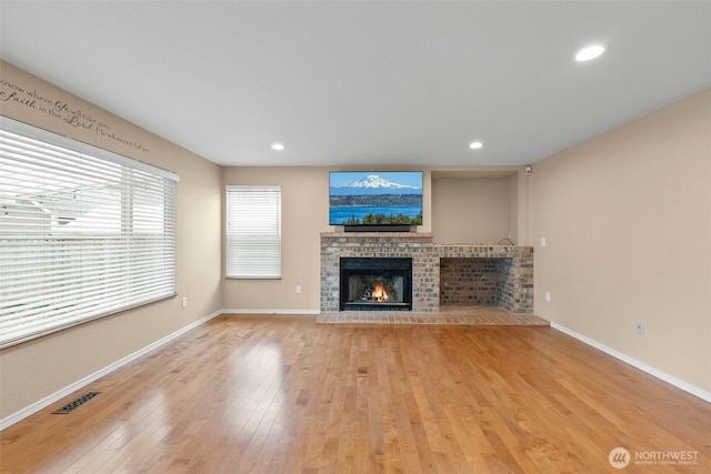 unfurnished living room with recessed lighting, a fireplace, visible vents, baseboards, and light wood-type flooring