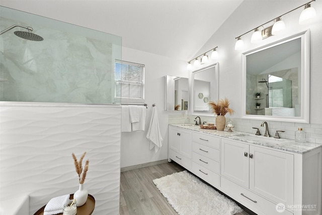 full bathroom featuring wood finished floors, vaulted ceiling, a sink, and a walk in shower