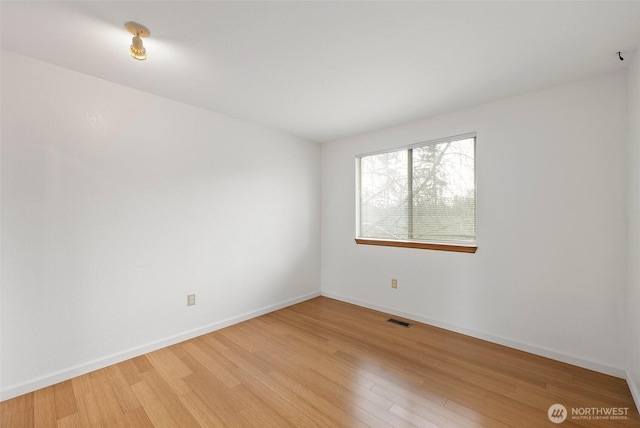 unfurnished room featuring baseboards, visible vents, and light wood finished floors