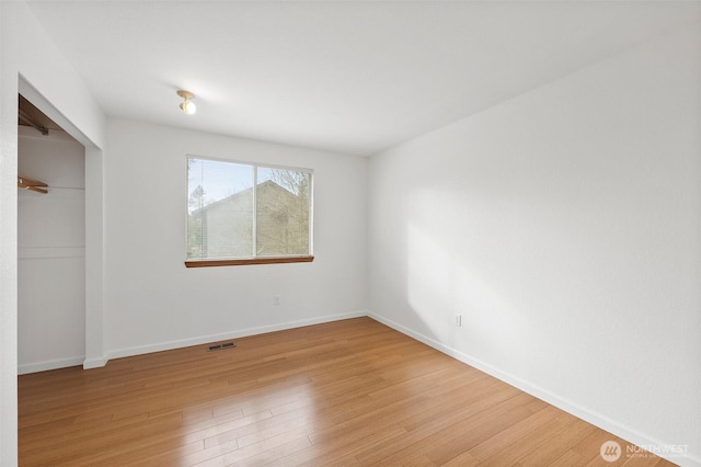 unfurnished bedroom featuring a closet, visible vents, light wood-style flooring, and baseboards