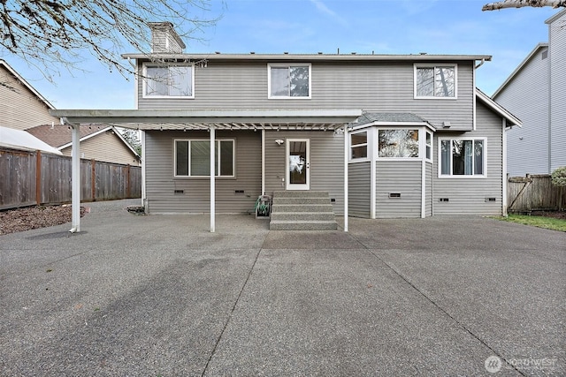 rear view of house with entry steps, a chimney, crawl space, fence, and a patio area