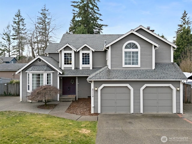 traditional-style house featuring an attached garage, fence, concrete driveway, and roof with shingles