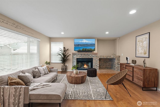 living area with recessed lighting, a brick fireplace, and wood finished floors